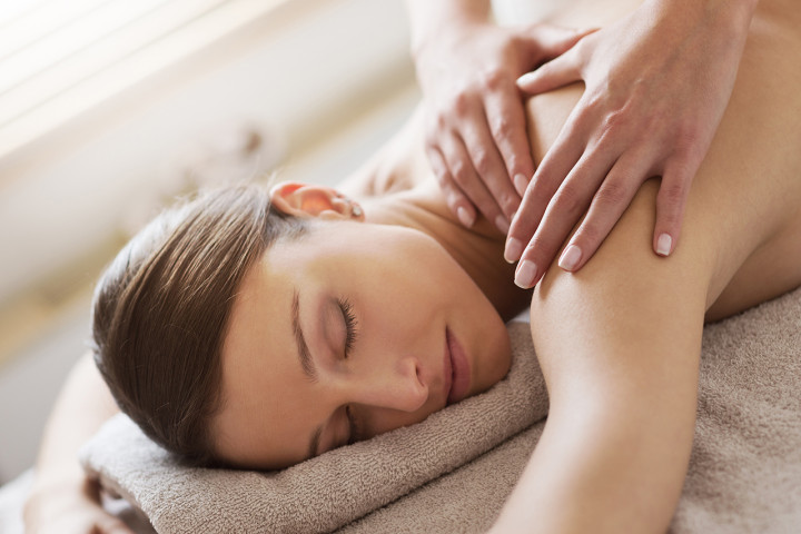 eine Frau, die auf einem Handtuch liegt uns massiert wird